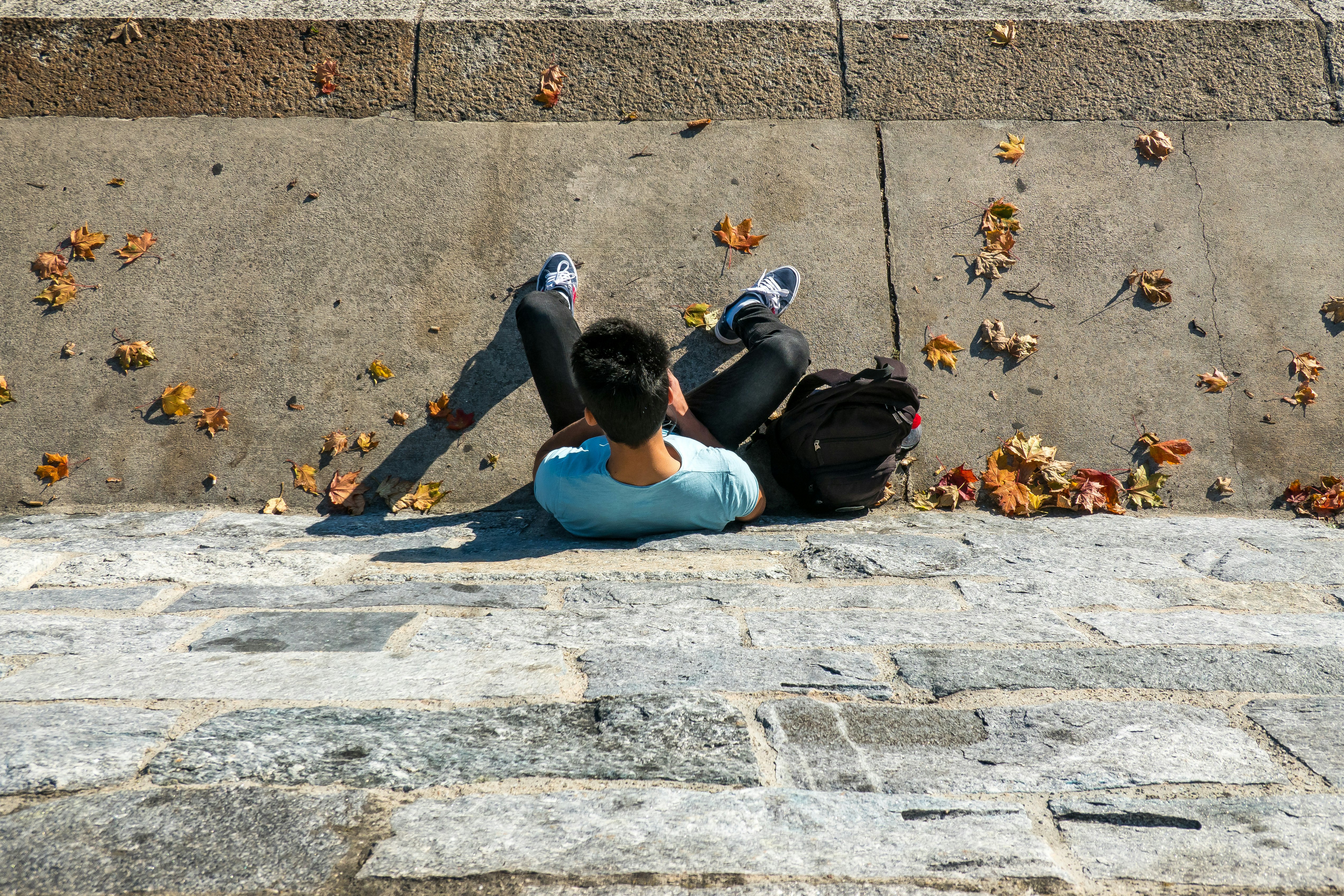 man in blue tank top and black pants lying on concrete floor